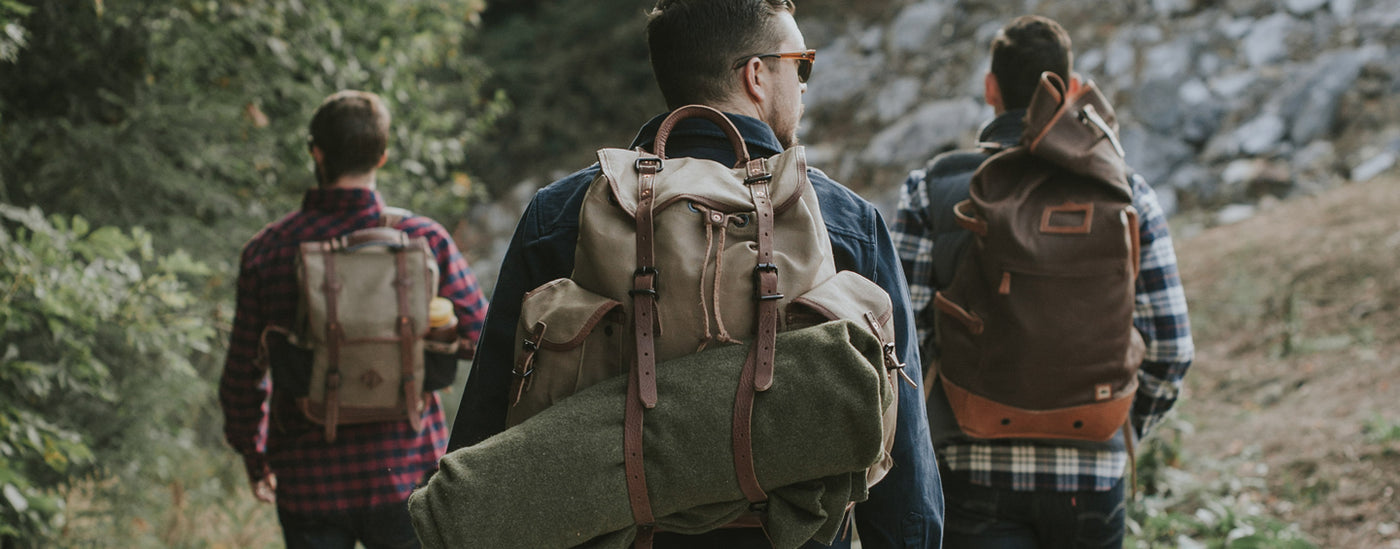 Group of three guys wearing rucksacks.