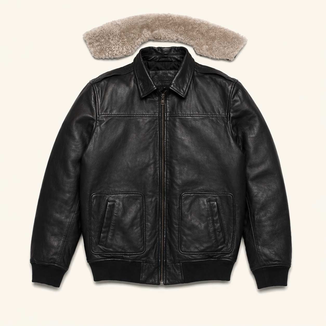 Close-up of detachable sherpa collar on black leather bomber jacket, button-on snap system for adjustable warmth