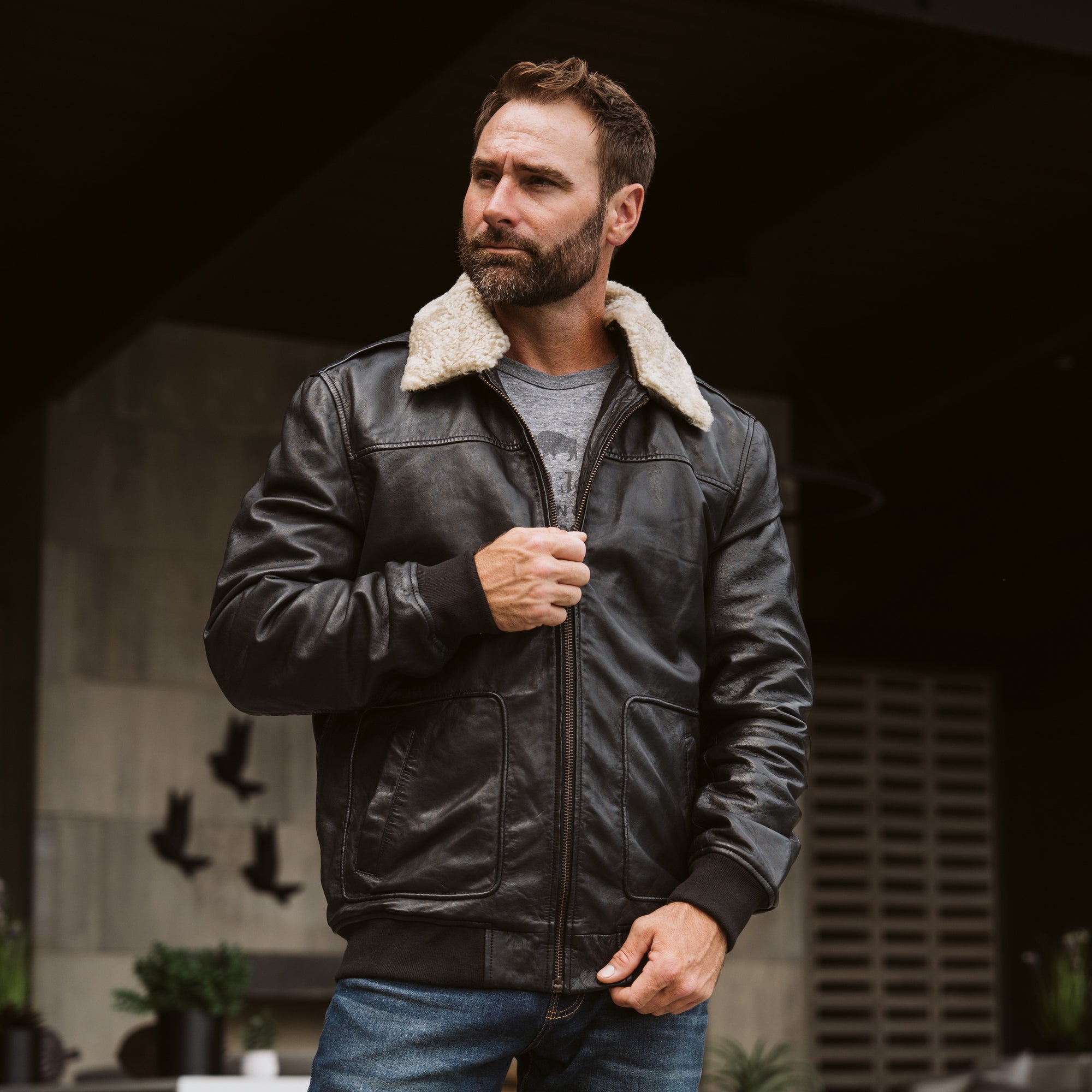 Lifestyle image of man wearing Buffalo Jackson black leather aviator bomber jacket outdoors, rugged vintage styling