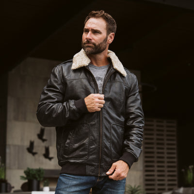 Lifestyle image of man wearing Buffalo Jackson black leather aviator bomber jacket outdoors, rugged vintage styling