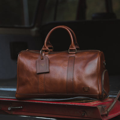 High-quality leather duffle with robust carry handles, adjustable shoulder strap, and large zippered opening.