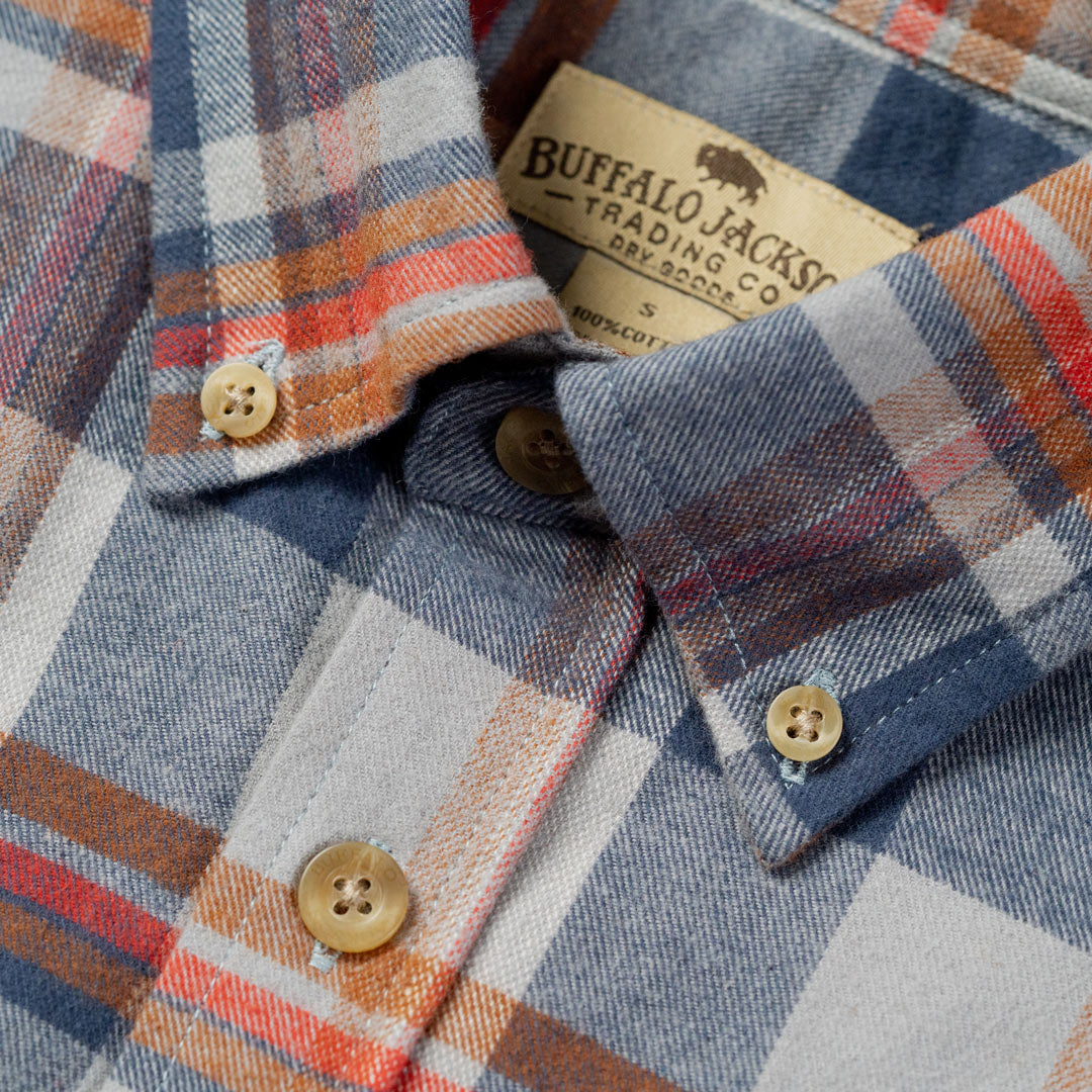 Plaid shirt with buttons and a visible brand label on a close-up of the collar.