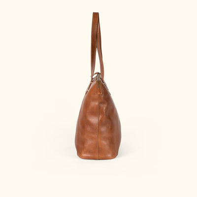 Front view of the Walker rustic tan leather tote with its tapered panels and edge stitching