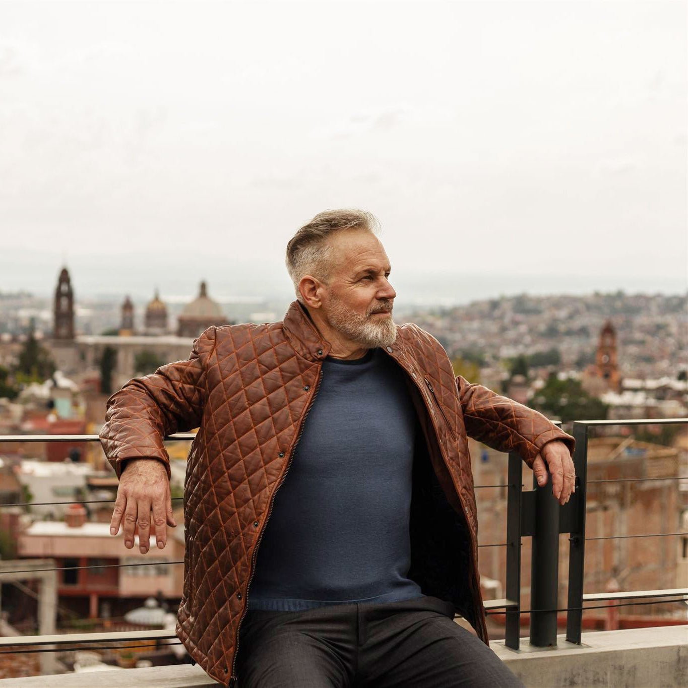 Man on a rooftop wearing the Highlands Quilted Leather Jacket in Whiskey Brown