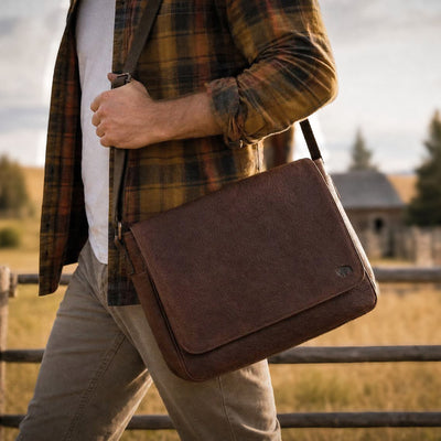 A brown full grain leather messenger bag with a structured body and a shoulder strap.