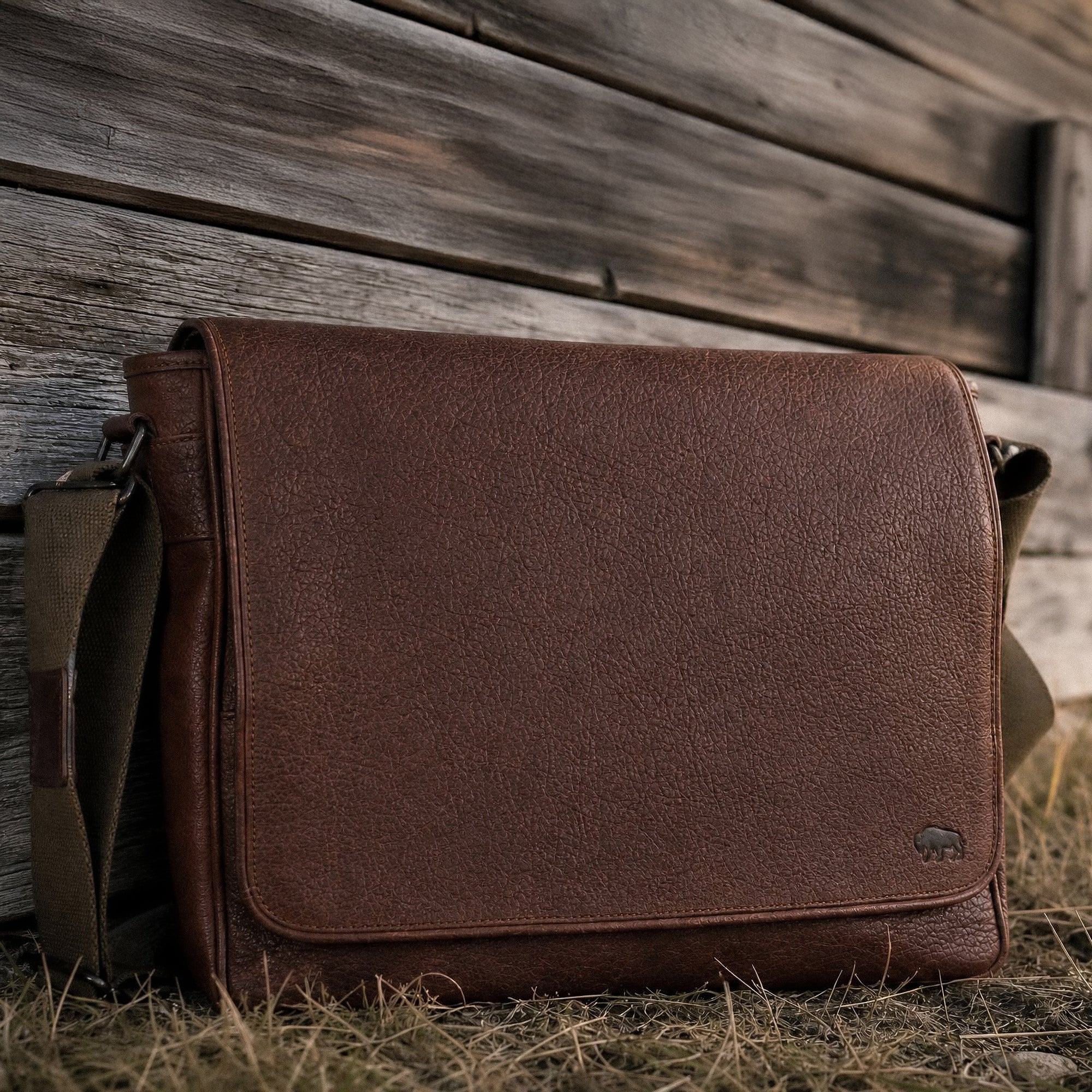 Brown leather bag leaning against a wooden wall.
