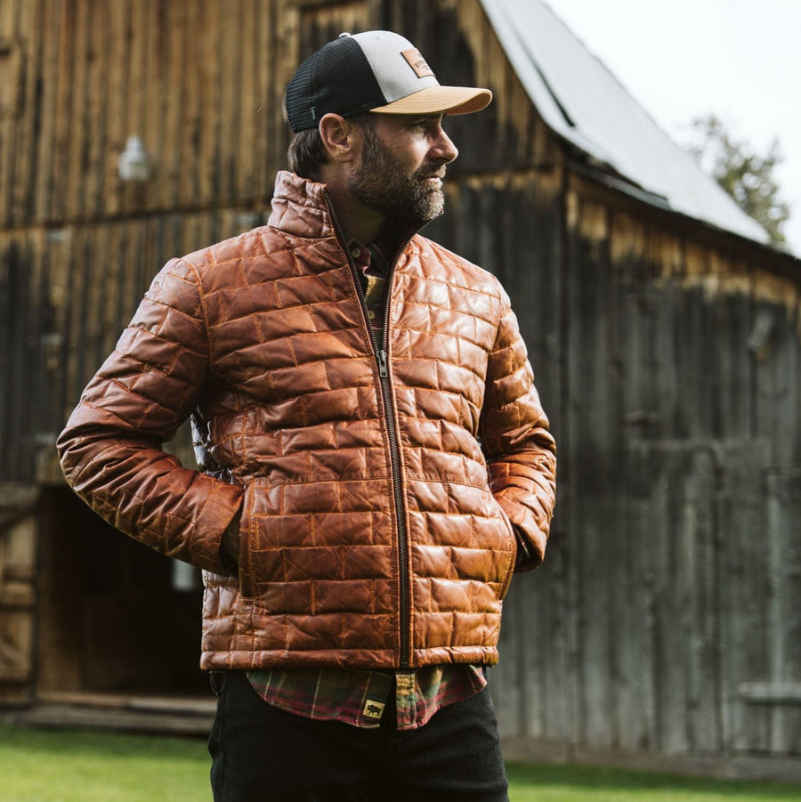 A whiskey brown, full-grain leather down filled jacket with a quilted pattern and YKK antique brass zippers.