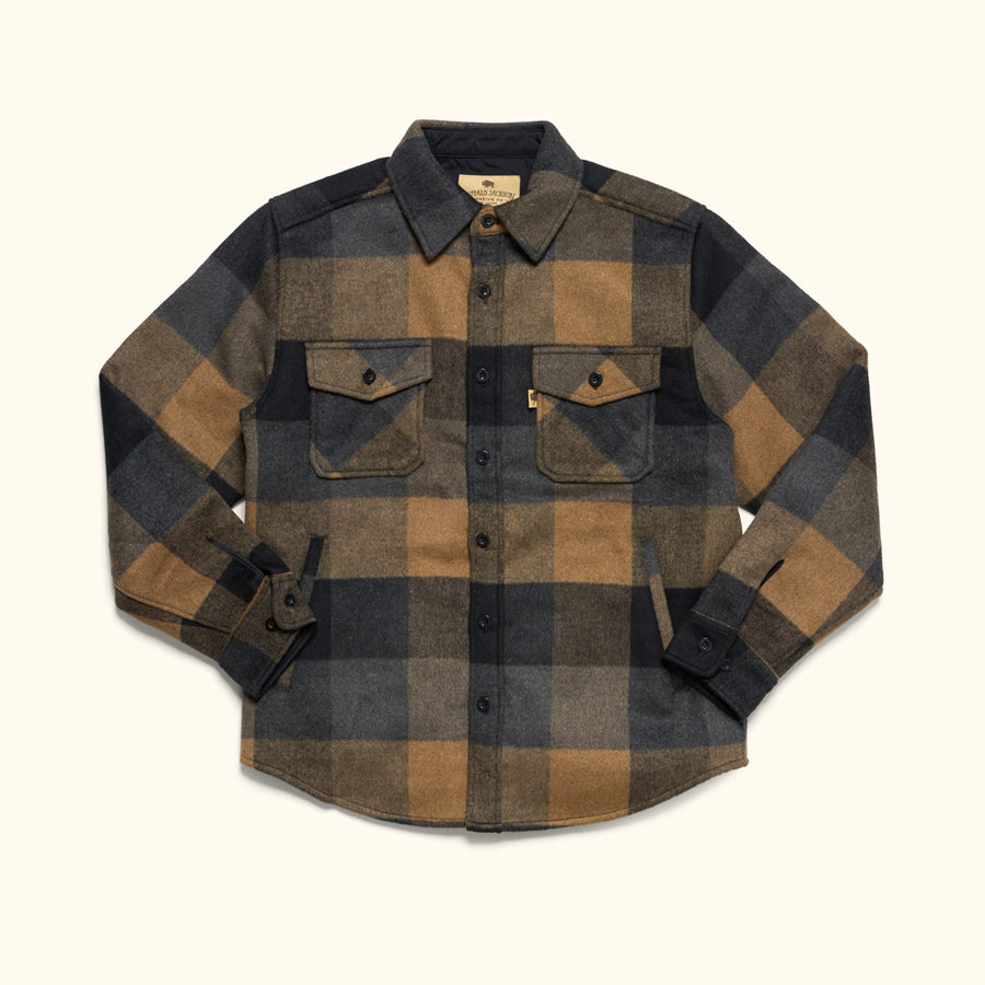 Man wearing a plaid shirt standing in front of Jackson Hole shed sculpture