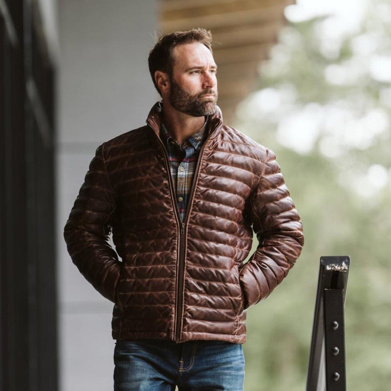 Buffalo Jackson Bridger Leather Down Jacket in dark brown lambskin worn outdoors in the mountains, real down under a full leather shell