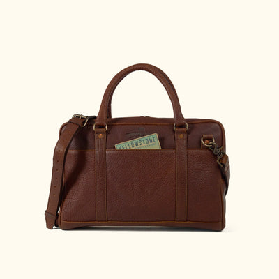 A brown leather laptop briefcase with a brass lock and a shoulder strap, set against a white background.