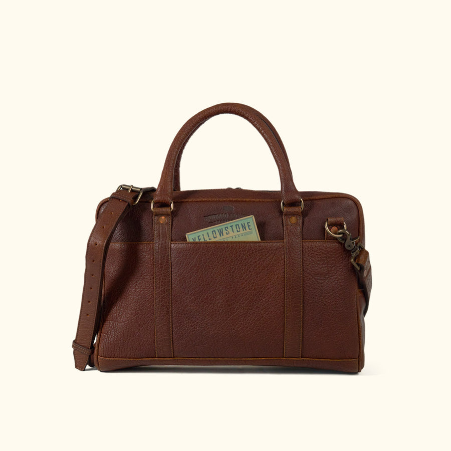 A brown leather laptop briefcase with a brass lock and a shoulder strap, set against a white background.