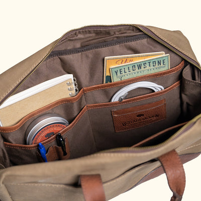 Canvas bag with leather straps and metal fastenings, emphasizing craftsmanship and rugged design.