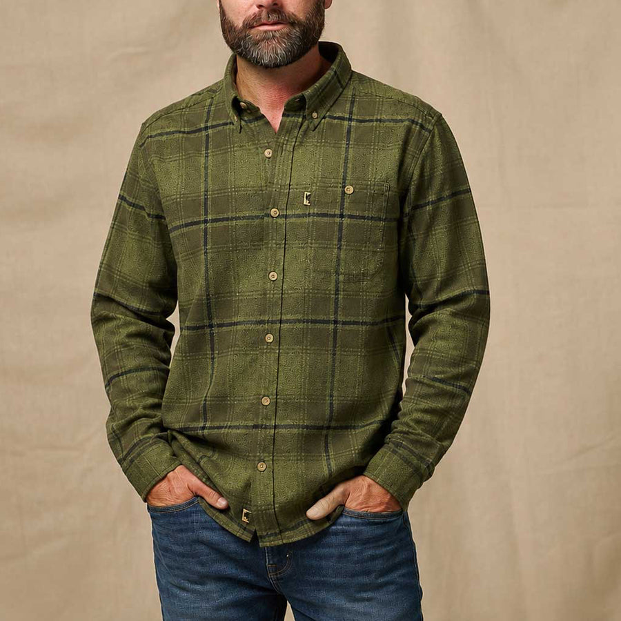 An olive green long-sleeve plaid button-down shirt with a chest pocket, laid flat against a light cream background.