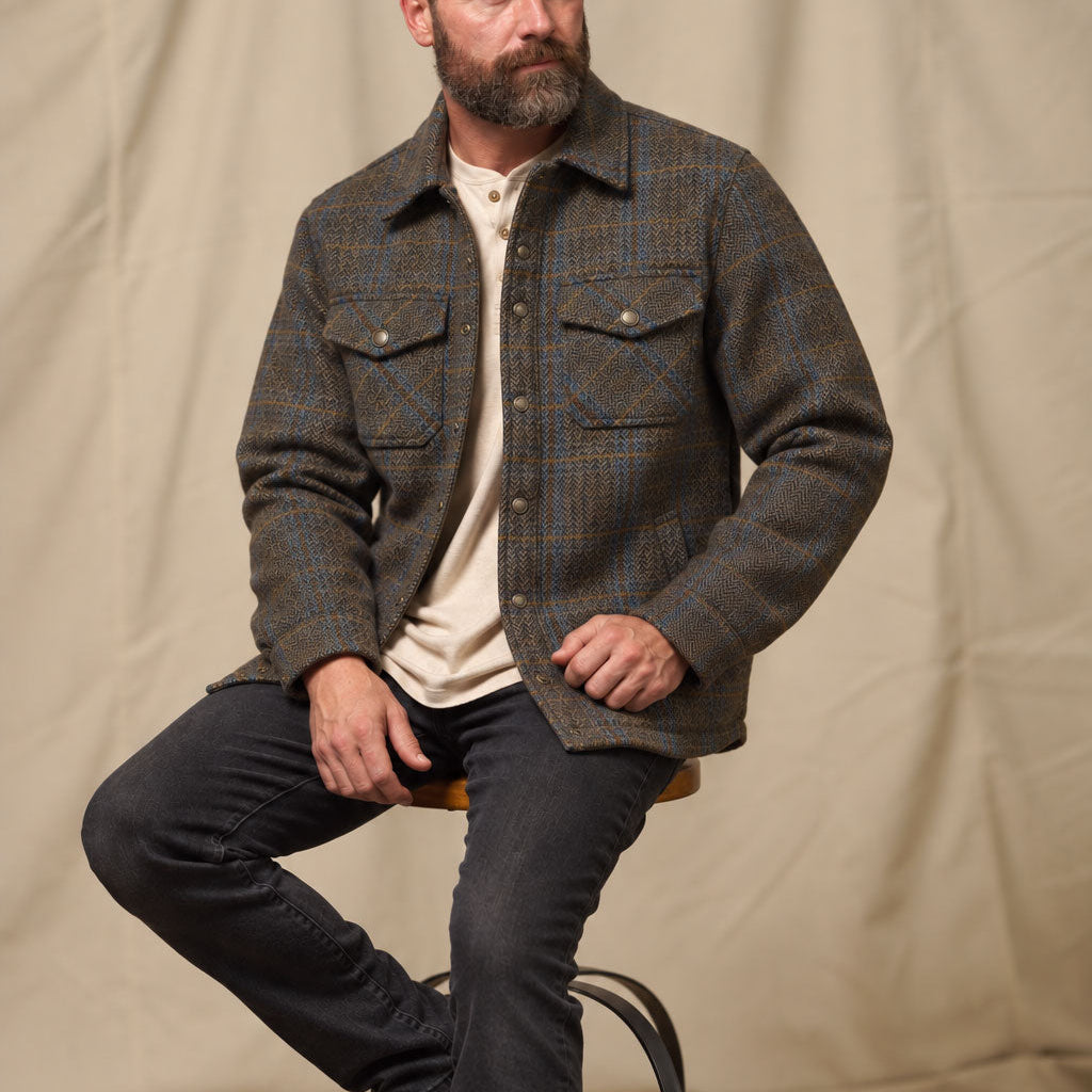 Man seated wearing the Aberdeen Wool Jacket in Thistle Bark Plaid