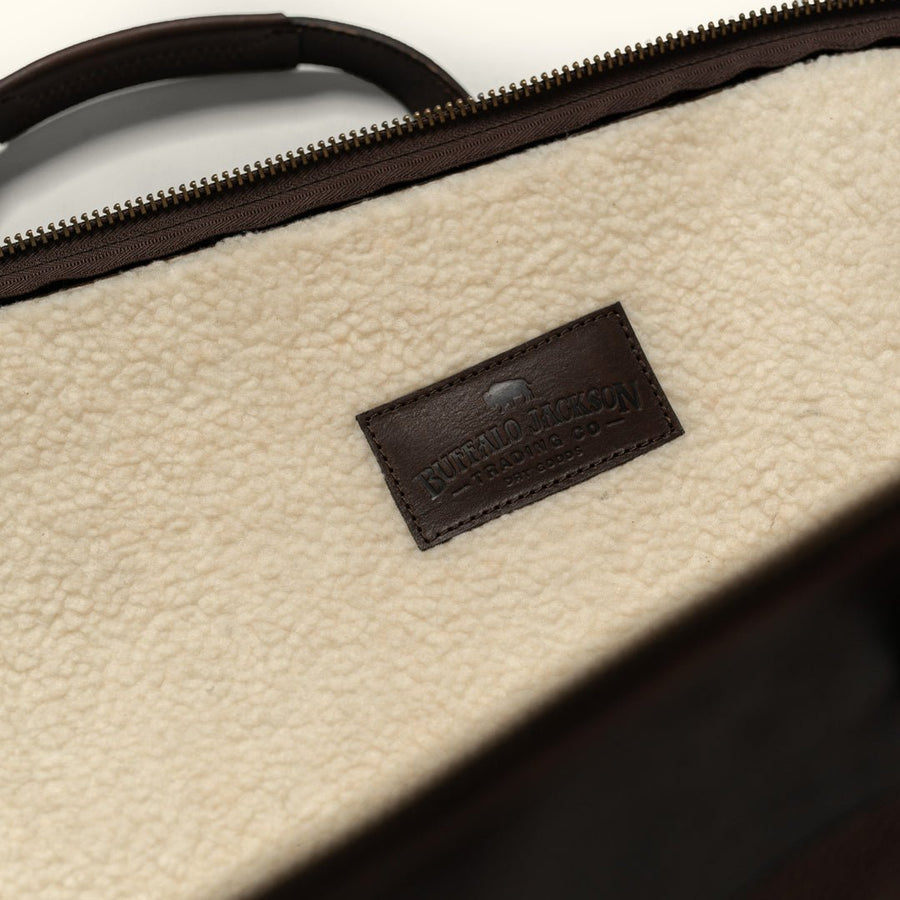 Interior sherpa wool lining of a leather rifle case with a stitched leather maker label