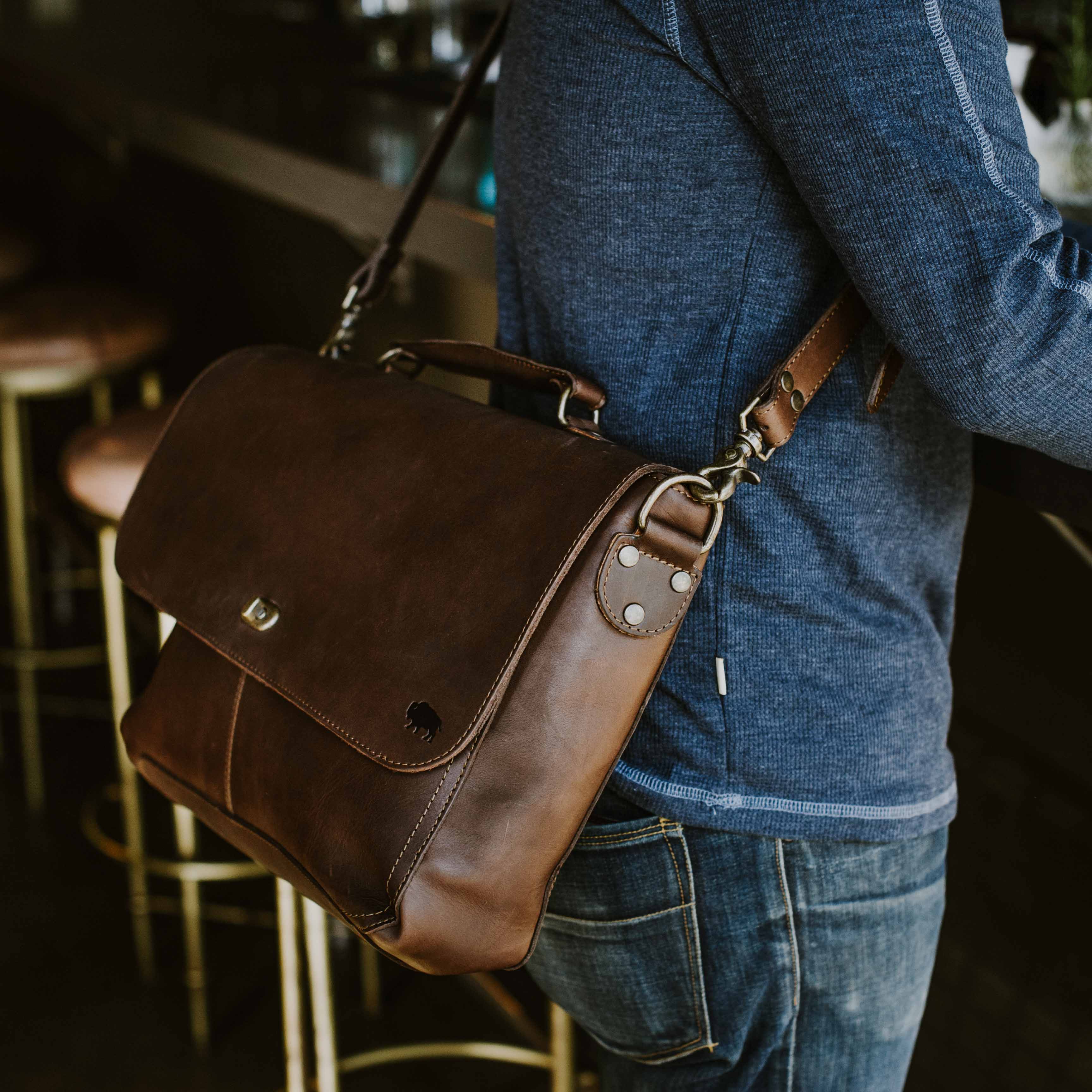 Man wearing the Roosevelt Leather Laptop Messenger Bag in Dark Oak across his body at a bar